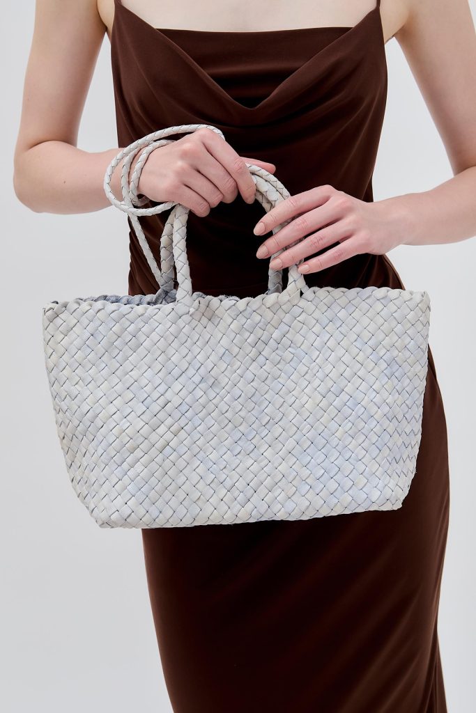 model handing a light colored middle bag