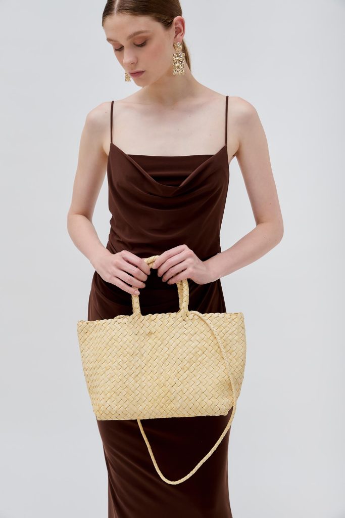 model handing a light colored middle bag